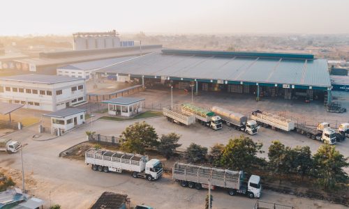 An aerial shot of factory trucks parked near the warehouse at daytime